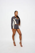 A woman modeling a charcoal long-sleeve jacket and matching shorts set with cream side panels and a white 'WYNHER' graphic on the chest, paired with clear high-heeled sandals, against a plain white studio background.